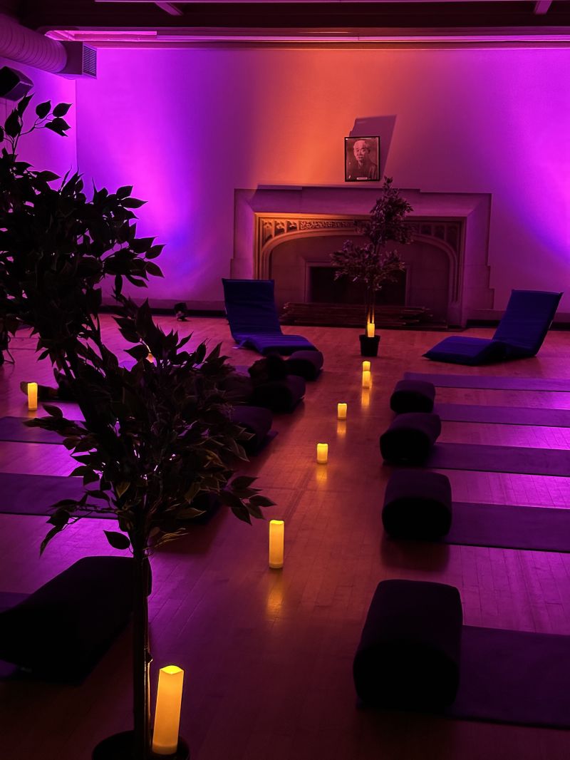 Dimly lit room with candles, plants, reclining chairs and mats. Soothing nature videos are projected onto the wall.