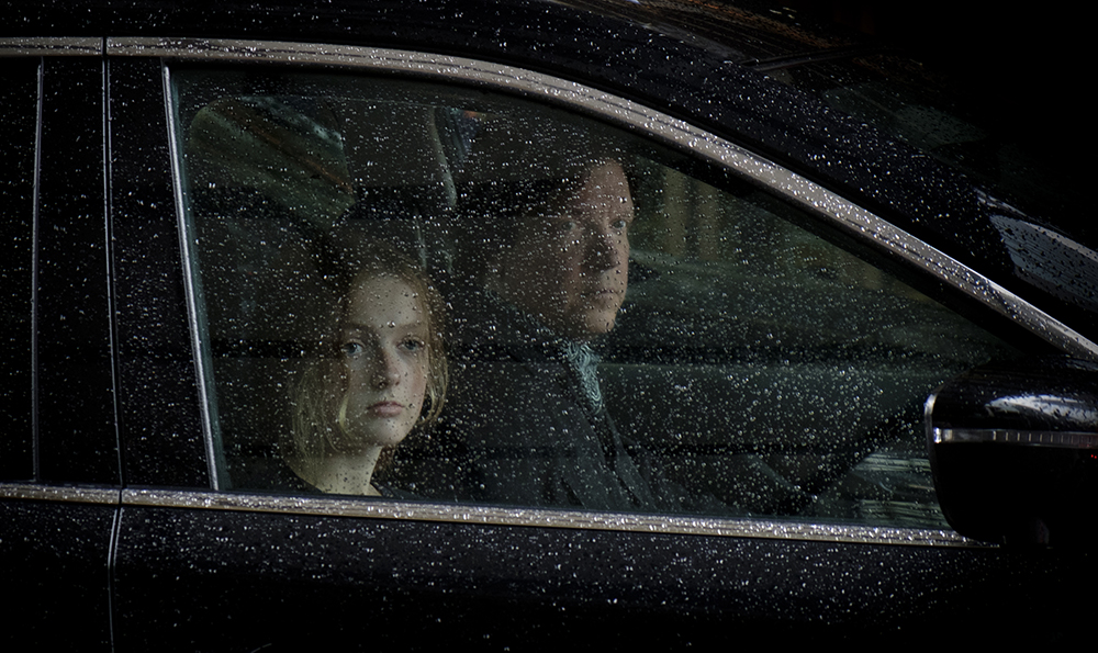 A man and a girl in a vehicle on a rainy day. 