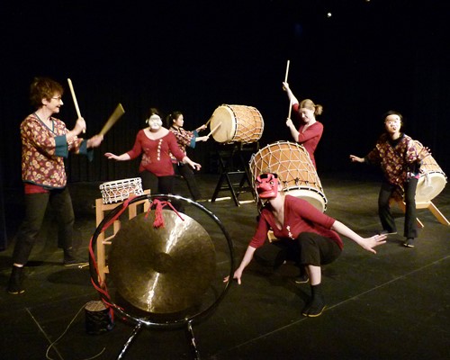 A group of masked Taiko performers on stage.