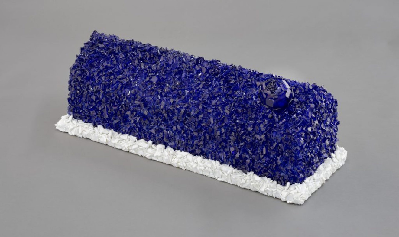 Image of Tim Whiten's work Respite. A blue and white rectangular object made up of crushed glass resting on the floor.