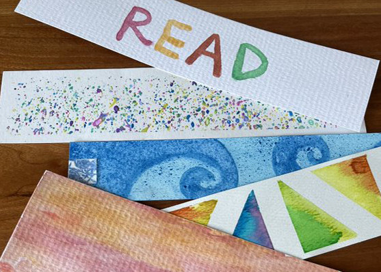 A set of colourful watercolour bookmarks on a wooden surface. 