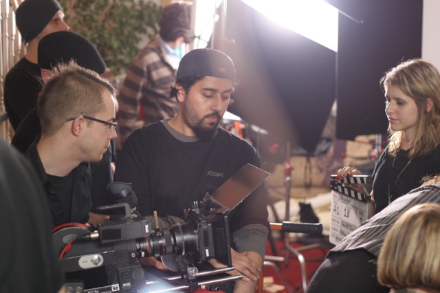 A group of filmmakers gathered in a studio setting, discussing a shot. 