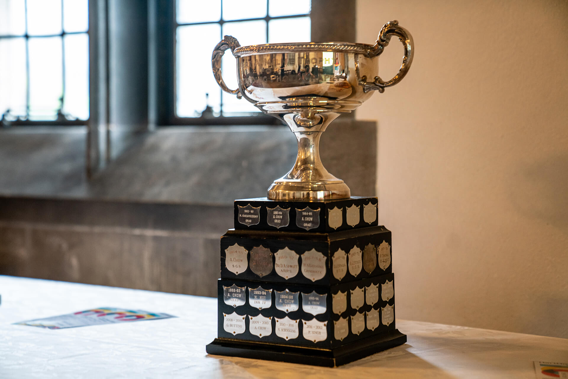 a silver cup as award displaying on a table in front of a window
