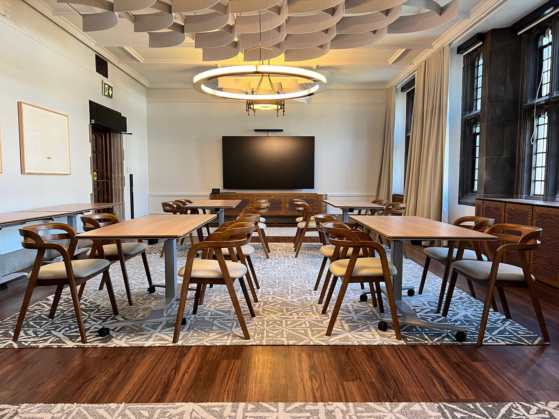 Fully renovated room with tables set for meetings, an interactive screen and sound technology